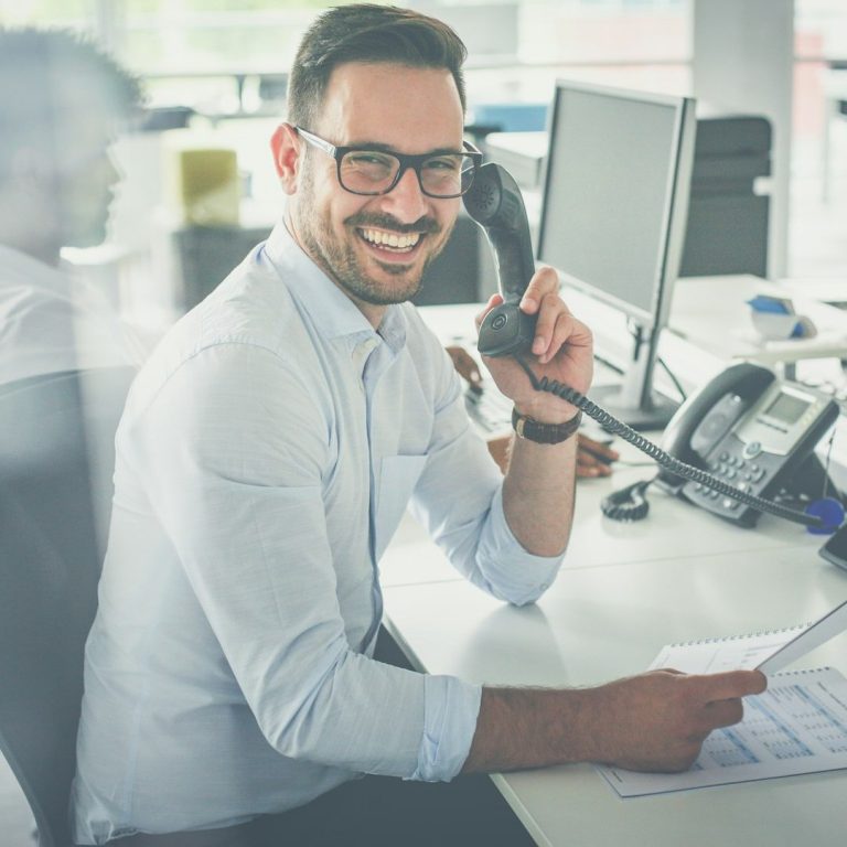Un homme souriant tient un téléphone à la main
